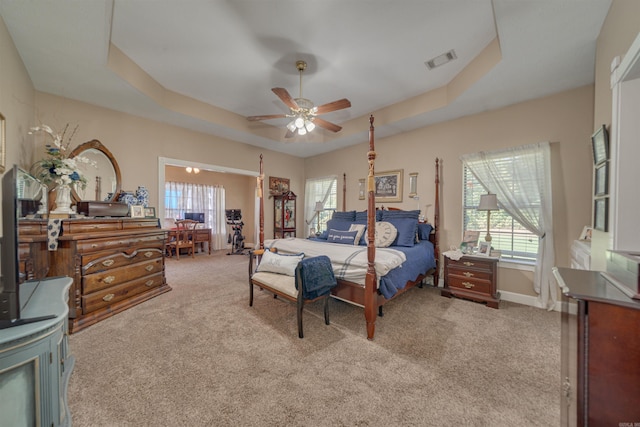 bedroom featuring ceiling fan, a raised ceiling, and light colored carpet