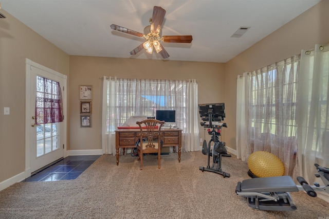 exercise room with ceiling fan and dark tile patterned floors