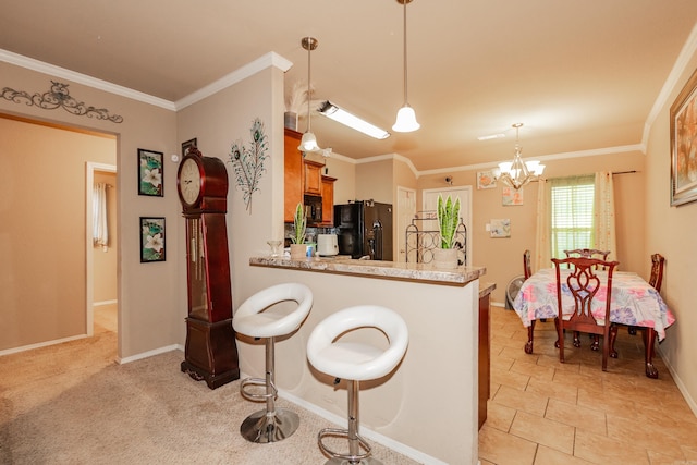 kitchen featuring kitchen peninsula, ornamental molding, black appliances, a breakfast bar, and decorative light fixtures