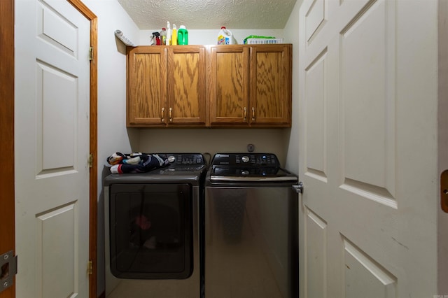 laundry room featuring cabinets, washer and dryer, and a textured ceiling