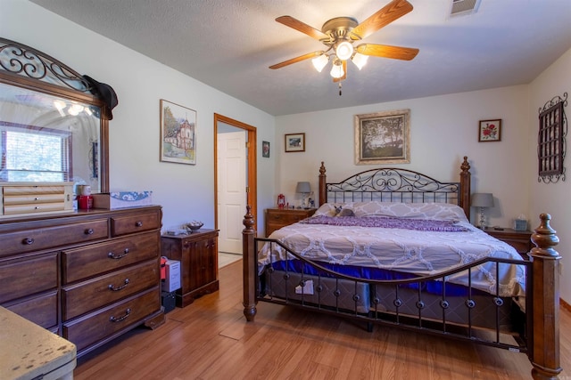 bedroom with ceiling fan, a textured ceiling, and light hardwood / wood-style flooring