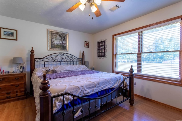 bedroom featuring hardwood / wood-style flooring, a textured ceiling, and ceiling fan