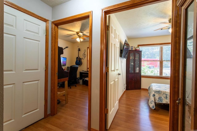 hall featuring light hardwood / wood-style floors and a textured ceiling