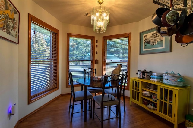 dining space with dark wood-type flooring and a chandelier