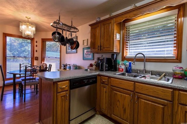 kitchen with decorative light fixtures, sink, hardwood / wood-style flooring, stainless steel dishwasher, and a chandelier