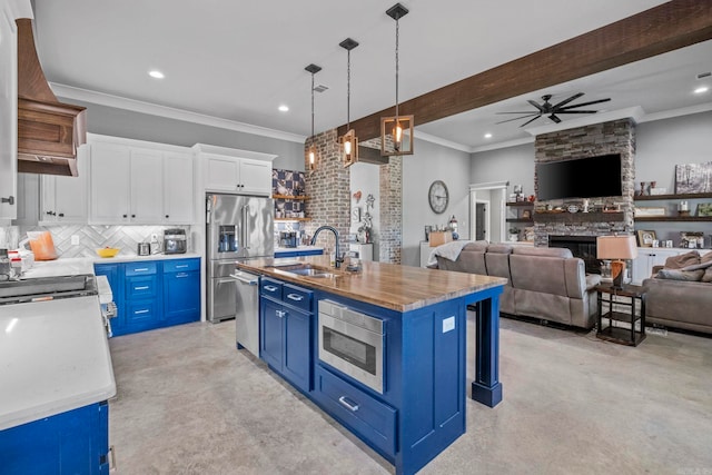 kitchen with hanging light fixtures, a center island with sink, sink, blue cabinetry, and white cabinetry