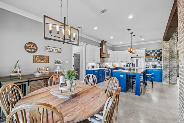 dining area featuring ornamental molding, a chandelier, sink, and brick wall