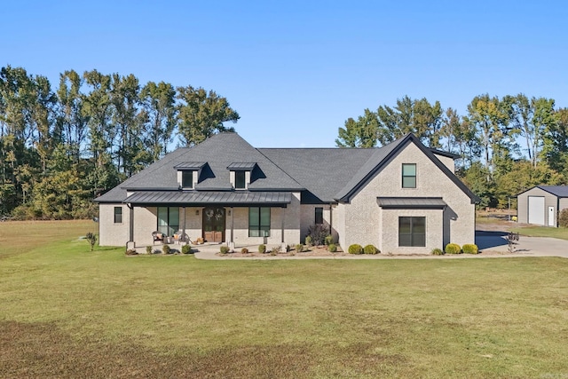 modern farmhouse with a front lawn, covered porch, an outbuilding, and a garage