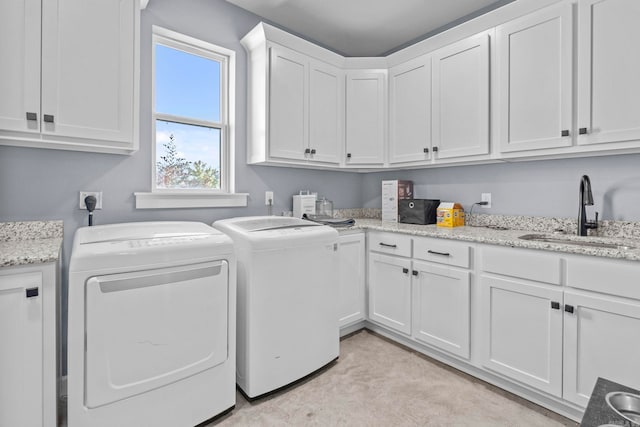 washroom featuring sink, washing machine and dryer, and cabinets