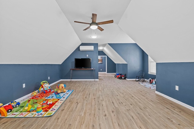 game room with a wall mounted air conditioner, ceiling fan, light wood-type flooring, and vaulted ceiling