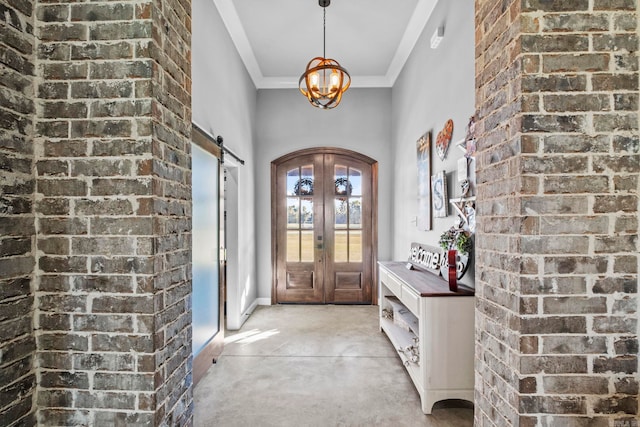 foyer with ornamental molding, french doors, a barn door, and a notable chandelier