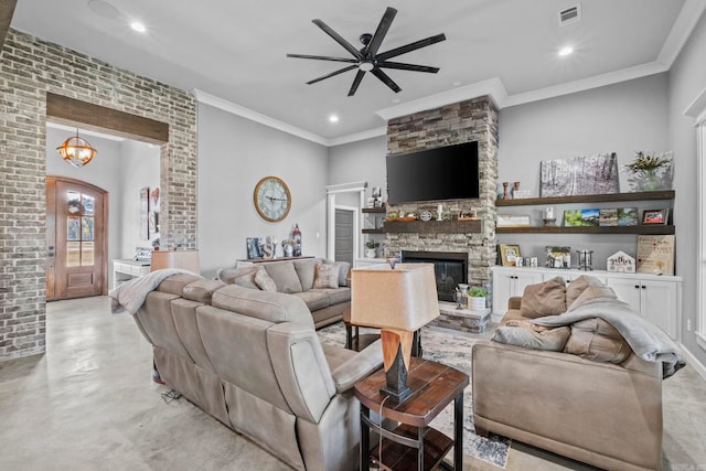 living room featuring ornamental molding, a stone fireplace, and ceiling fan with notable chandelier