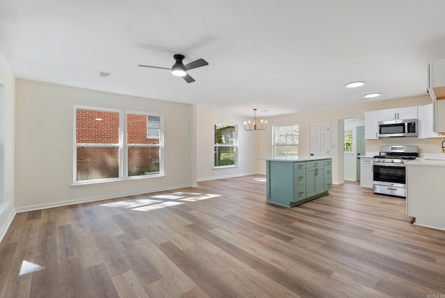 kitchen featuring light hardwood / wood-style flooring, stainless steel appliances, green cabinets, pendant lighting, and white cabinets