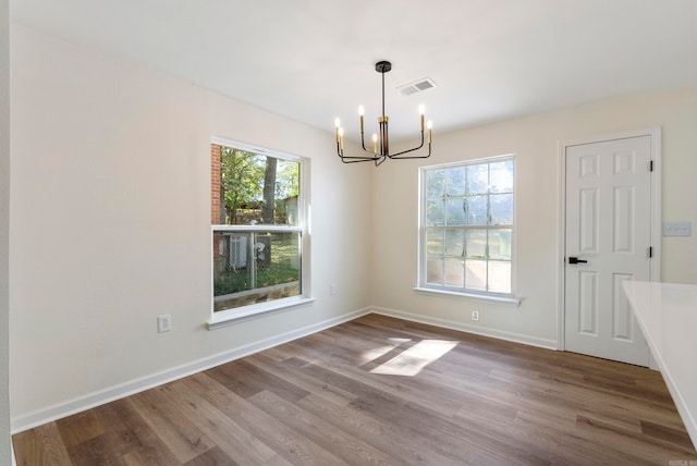 unfurnished dining area with an inviting chandelier and wood-type flooring