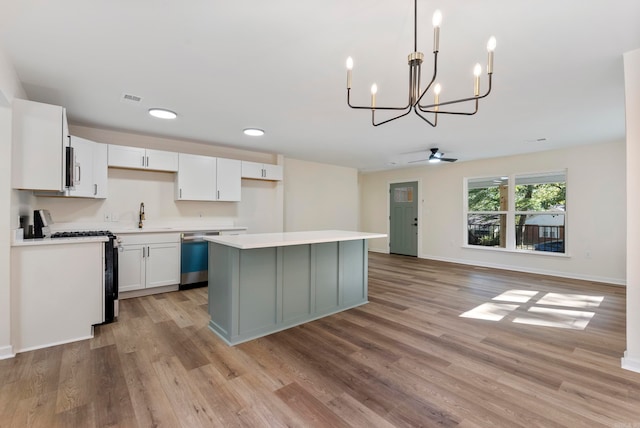 kitchen with light hardwood / wood-style floors, white cabinets, stainless steel appliances, and pendant lighting