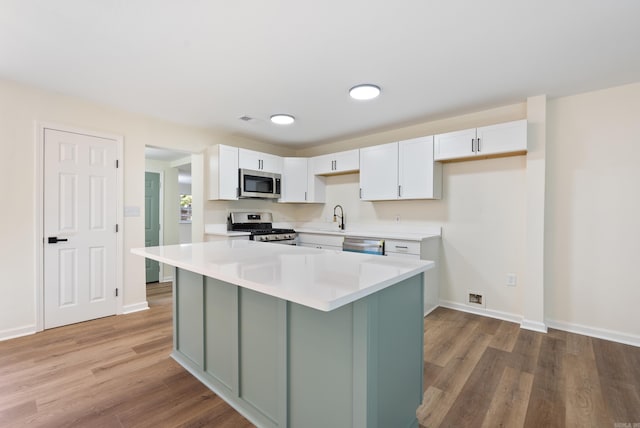 kitchen featuring appliances with stainless steel finishes, sink, a center island, white cabinetry, and light hardwood / wood-style floors