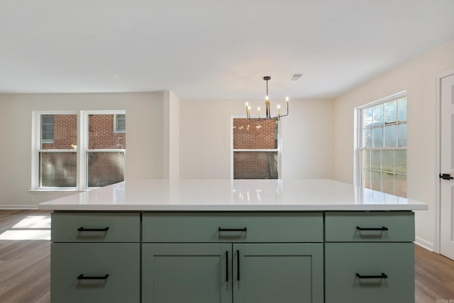 kitchen with an inviting chandelier, a center island, wood-type flooring, and green cabinetry