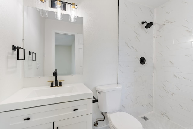 bathroom with vanity, toilet, and a tile shower