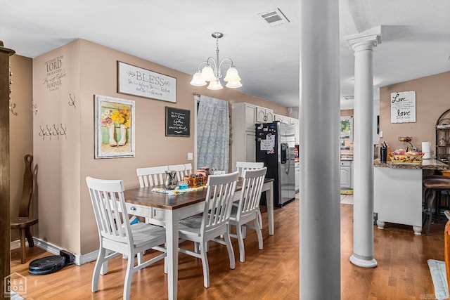 dining area featuring ornate columns, dark hardwood / wood-style flooring, and a chandelier