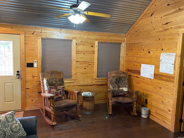 sitting room featuring lofted ceiling, dark wood-type flooring, and wooden walls