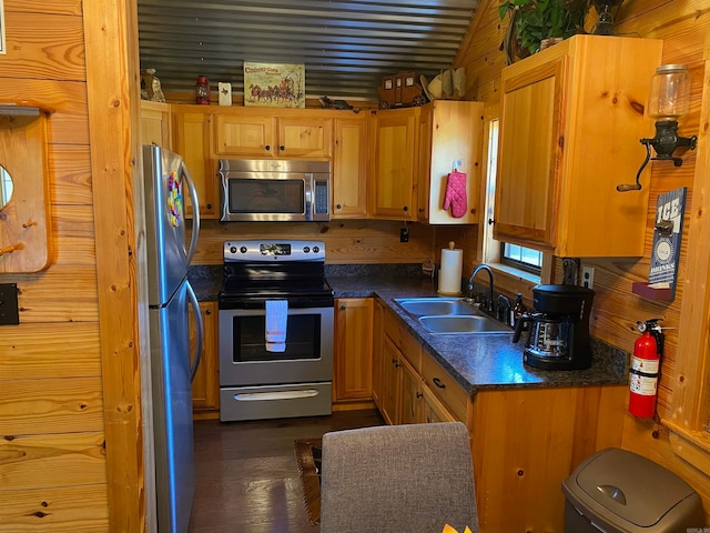 kitchen with sink, stainless steel appliances, wooden walls, and dark hardwood / wood-style flooring