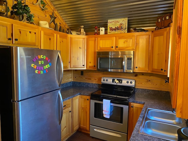 kitchen featuring wood walls, appliances with stainless steel finishes, and sink