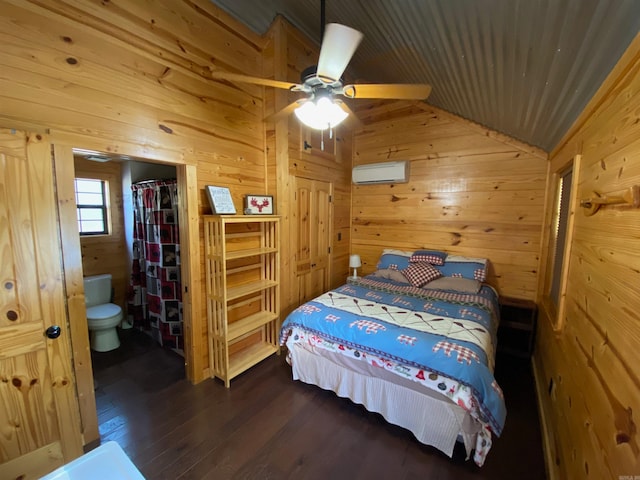 bedroom featuring lofted ceiling, ceiling fan, connected bathroom, dark hardwood / wood-style floors, and wooden walls