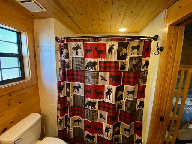 bathroom with wood ceiling, a shower with shower curtain, toilet, and wood walls