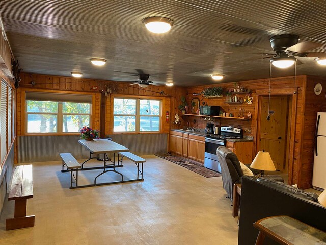 kitchen featuring white fridge, electric stove, wood walls, and sink