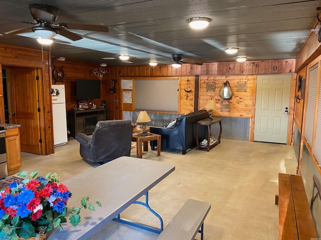 living room with ceiling fan and wood walls