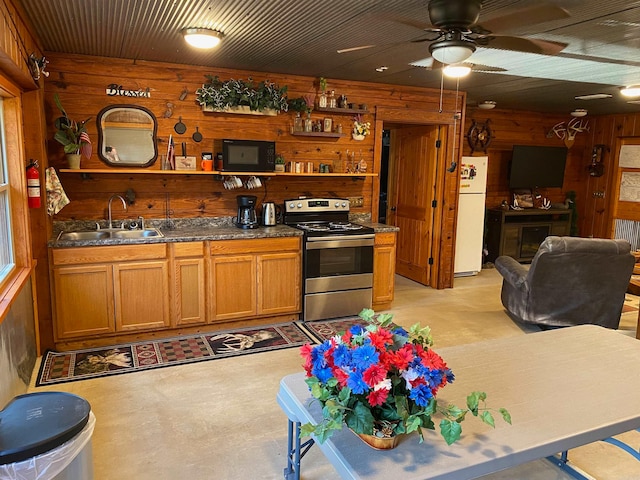 kitchen featuring wooden walls, sink, electric stove, white fridge, and ceiling fan