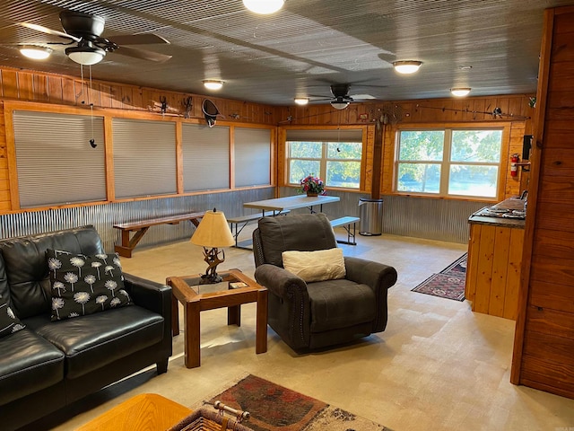 sitting room featuring wood walls, ceiling fan, light colored carpet, and plenty of natural light