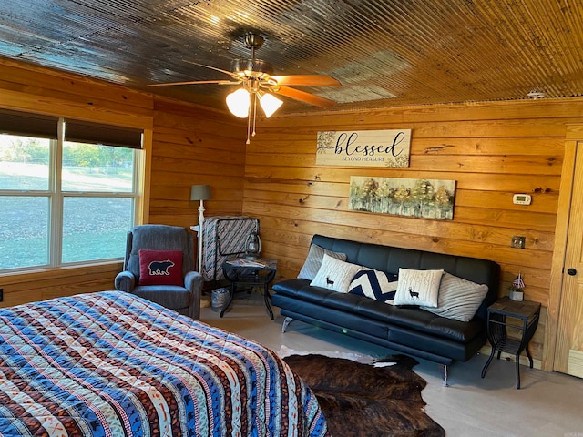 carpeted bedroom with wooden walls, a water view, and ceiling fan