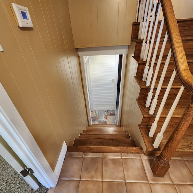 staircase featuring wood walls and tile patterned floors