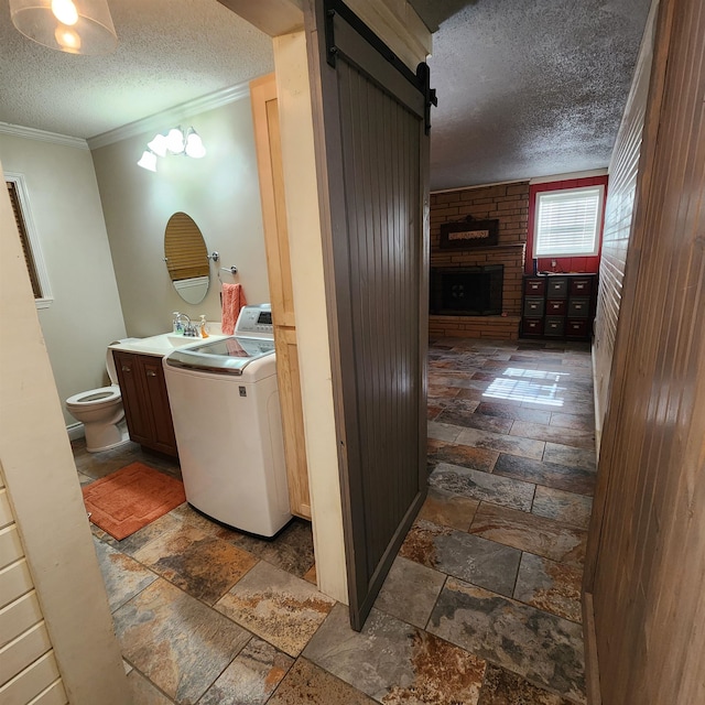 bathroom featuring a textured ceiling, washer / clothes dryer, a fireplace, vanity, and toilet