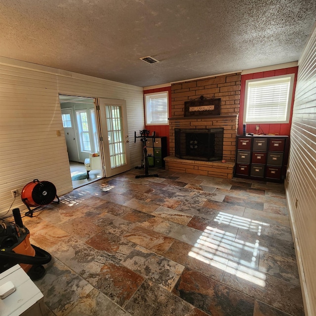 unfurnished living room featuring a stone fireplace and a textured ceiling