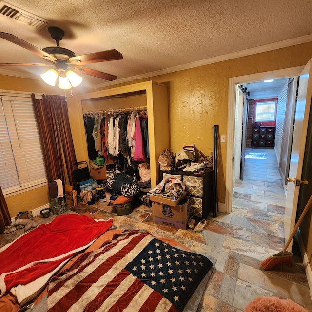 bedroom featuring ceiling fan, a textured ceiling, a closet, and crown molding