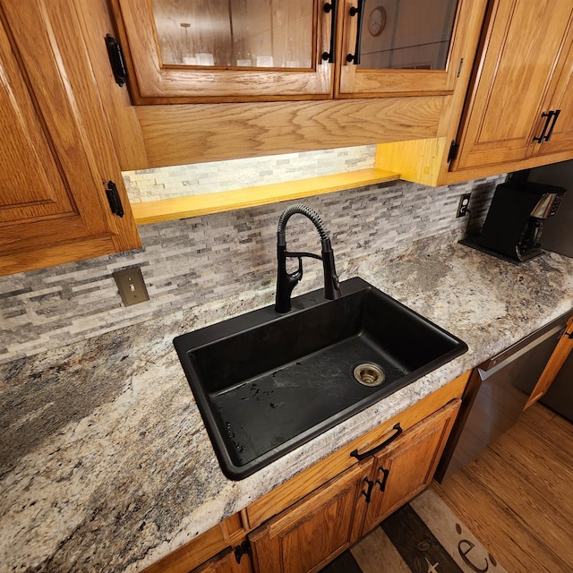 interior details with hardwood / wood-style floors, decorative backsplash, sink, and light stone countertops