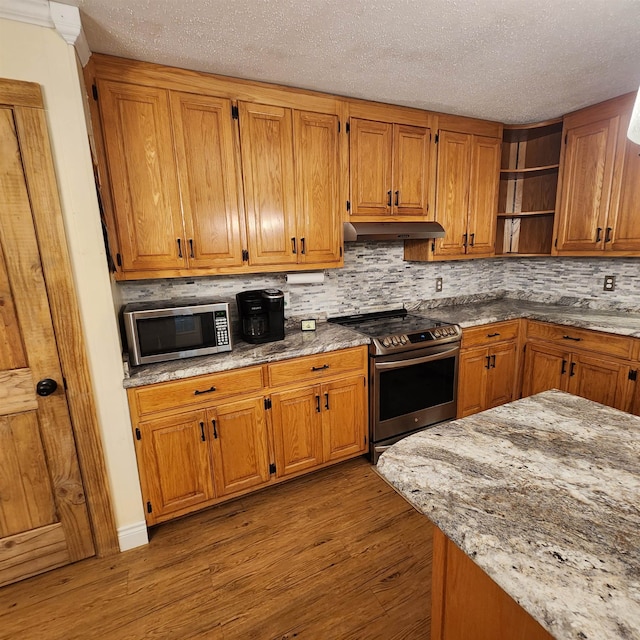 kitchen with a textured ceiling, stainless steel appliances, hardwood / wood-style flooring, and tasteful backsplash