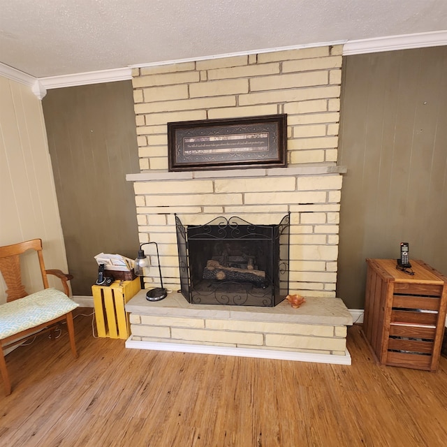 room details with wood-type flooring, a textured ceiling, a large fireplace, and crown molding