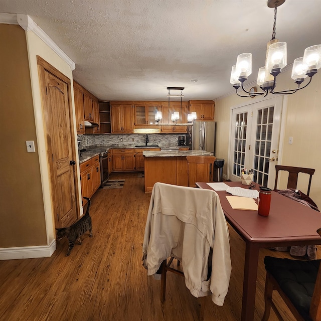 dining area with sink, ornamental molding, wood-type flooring, a chandelier, and french doors