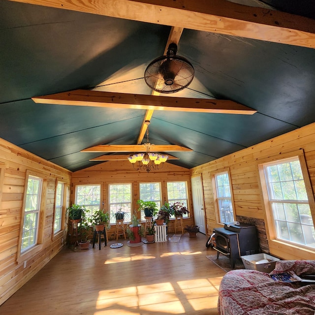 interior space featuring a healthy amount of sunlight, a wood stove, and lofted ceiling with beams