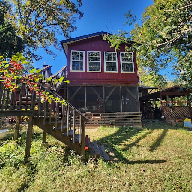 rear view of house featuring a lawn and a sunroom