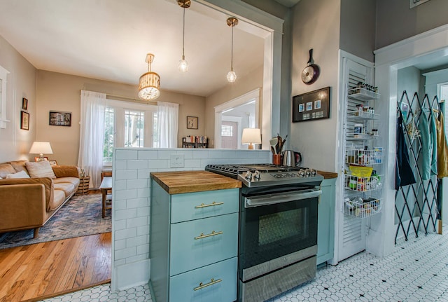 kitchen featuring light wood-type flooring, butcher block counters, stainless steel range oven, kitchen peninsula, and pendant lighting