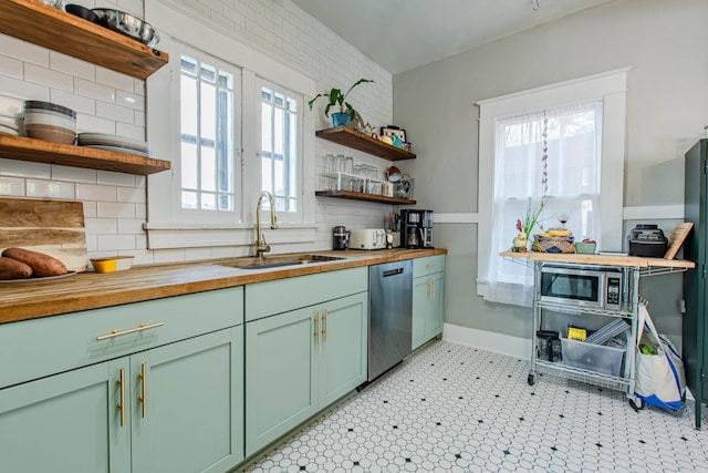 kitchen with butcher block countertops, stainless steel appliances, sink, and a wealth of natural light