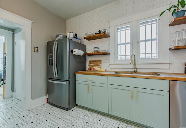 kitchen featuring wooden counters, sink, stainless steel appliances, and tasteful backsplash