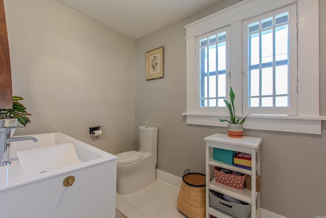 bathroom with toilet, sink, and tile patterned floors