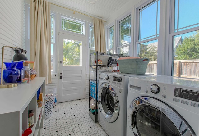 laundry area with light tile patterned floors, a healthy amount of sunlight, and washer and clothes dryer