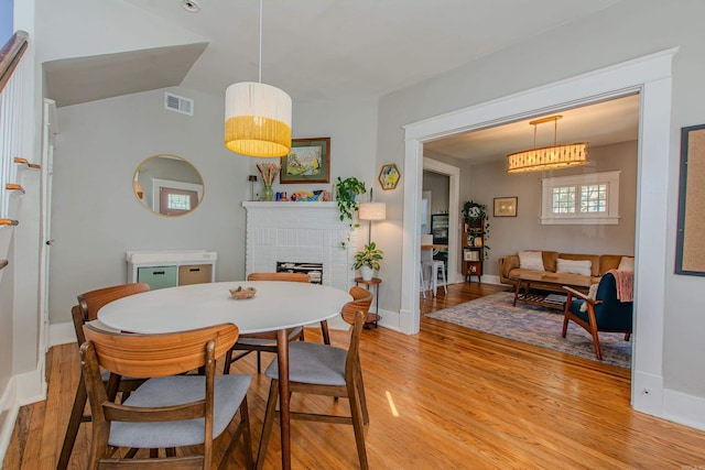 dining space featuring a brick fireplace and light hardwood / wood-style floors