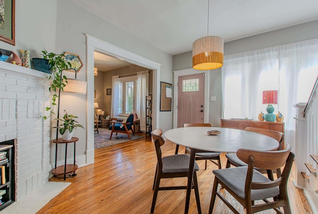 dining area featuring light hardwood / wood-style floors and a brick fireplace